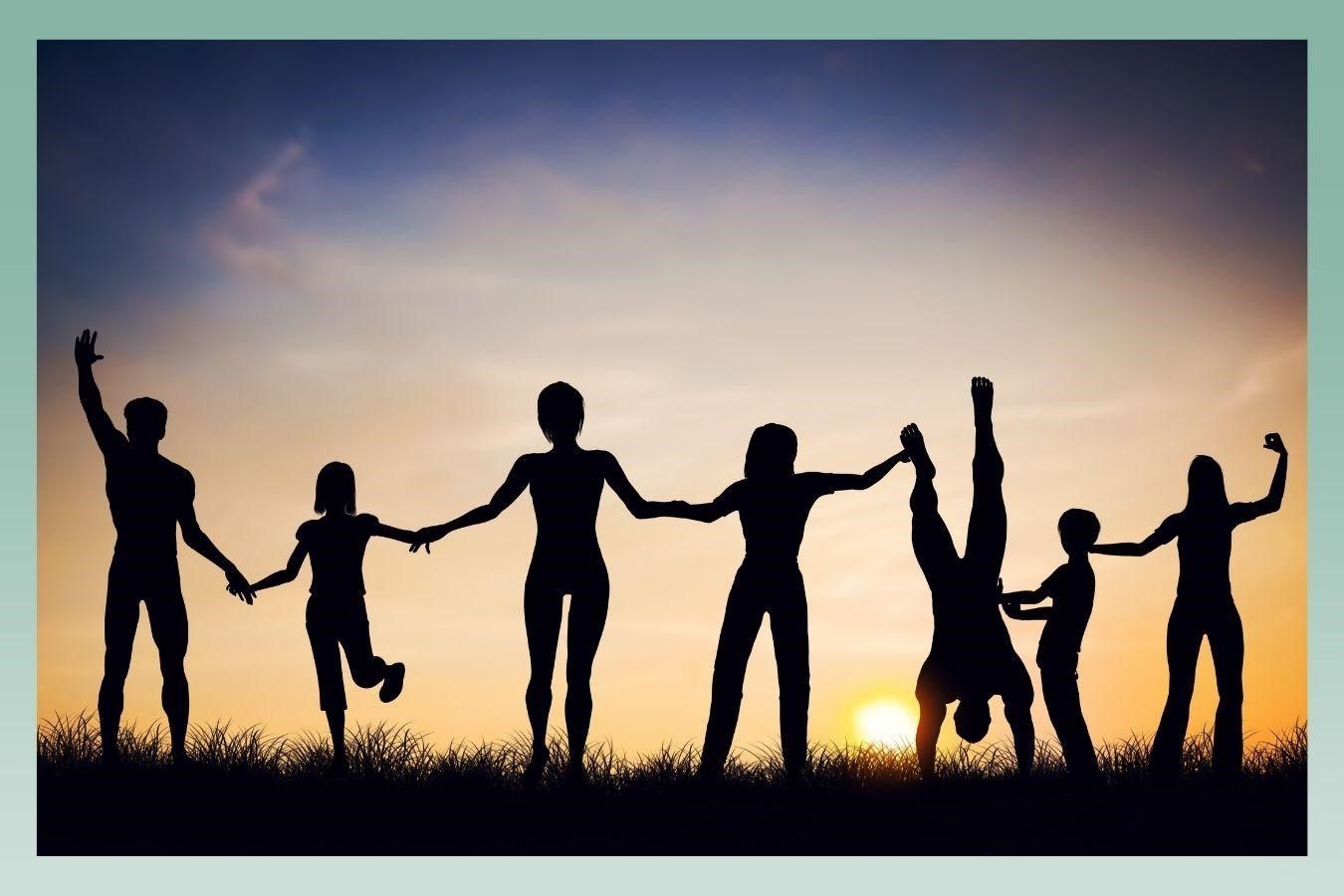Silhouetted people holding hands at sunset, one person doing a handstand, joyful and connected.