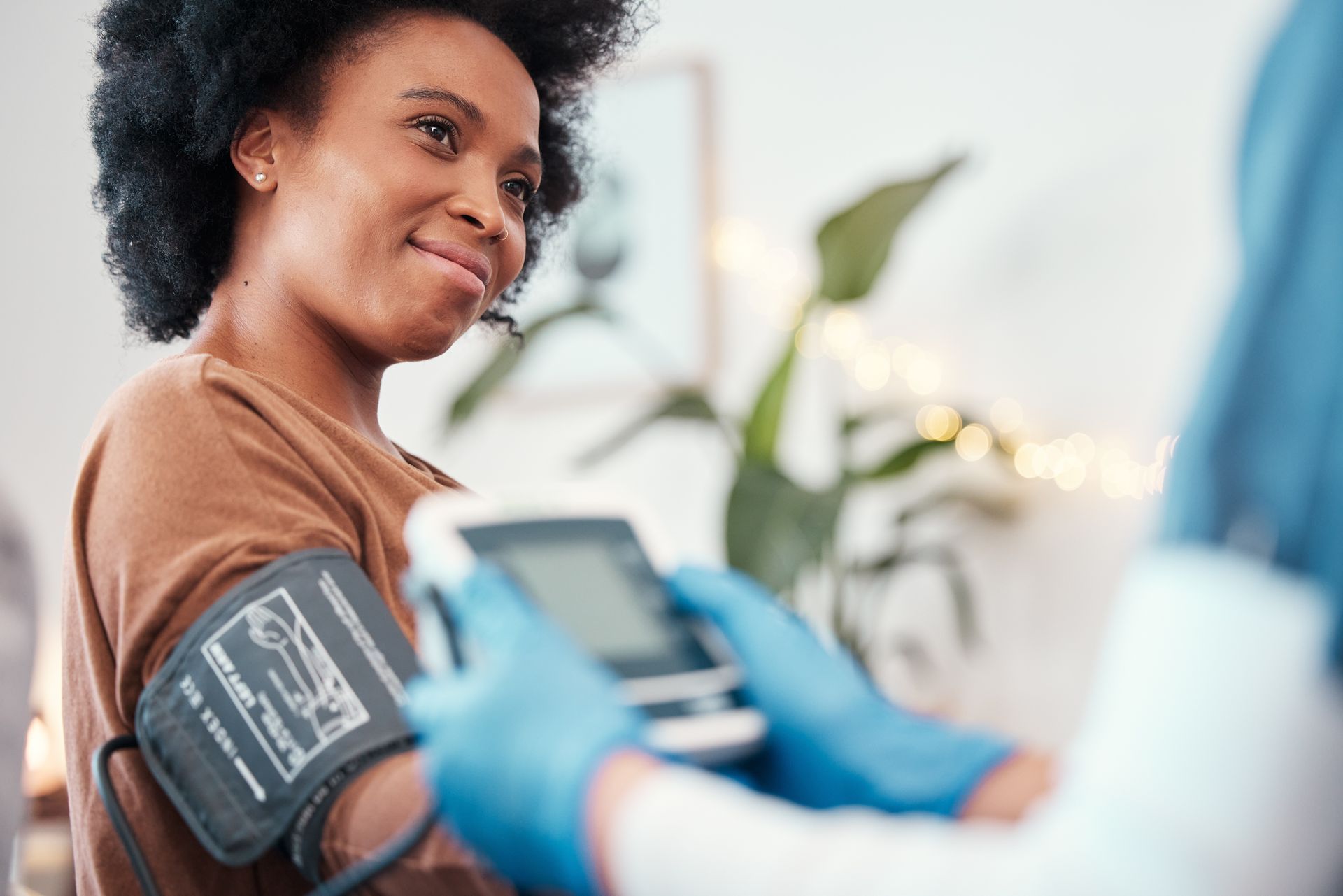 A medical professional takes a patient’s blood pressure in a clinic; the patient smiles.