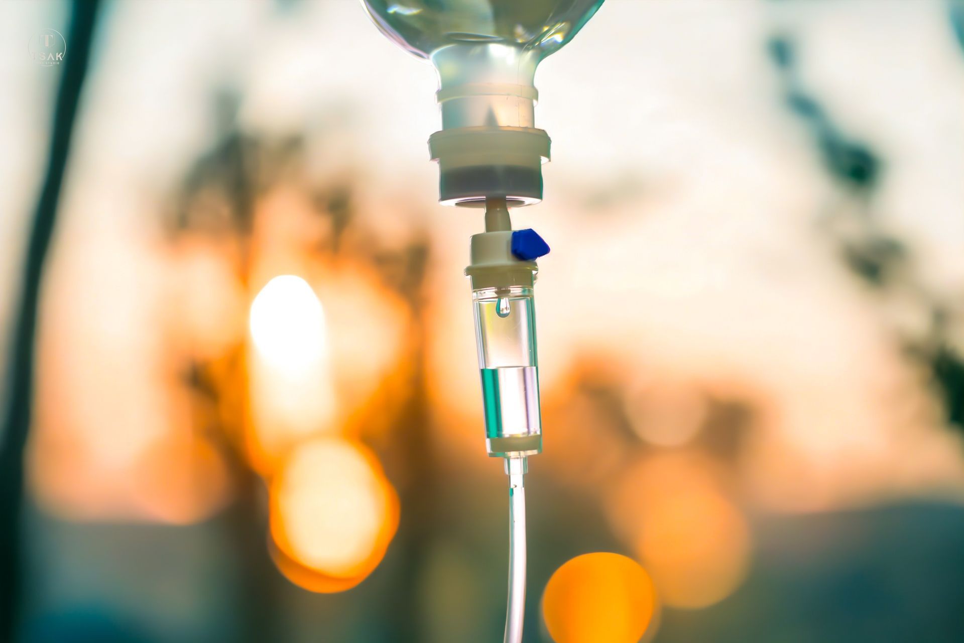 IV drip in a hospital setting, fluid flowing through a transparent tube, blurred background.