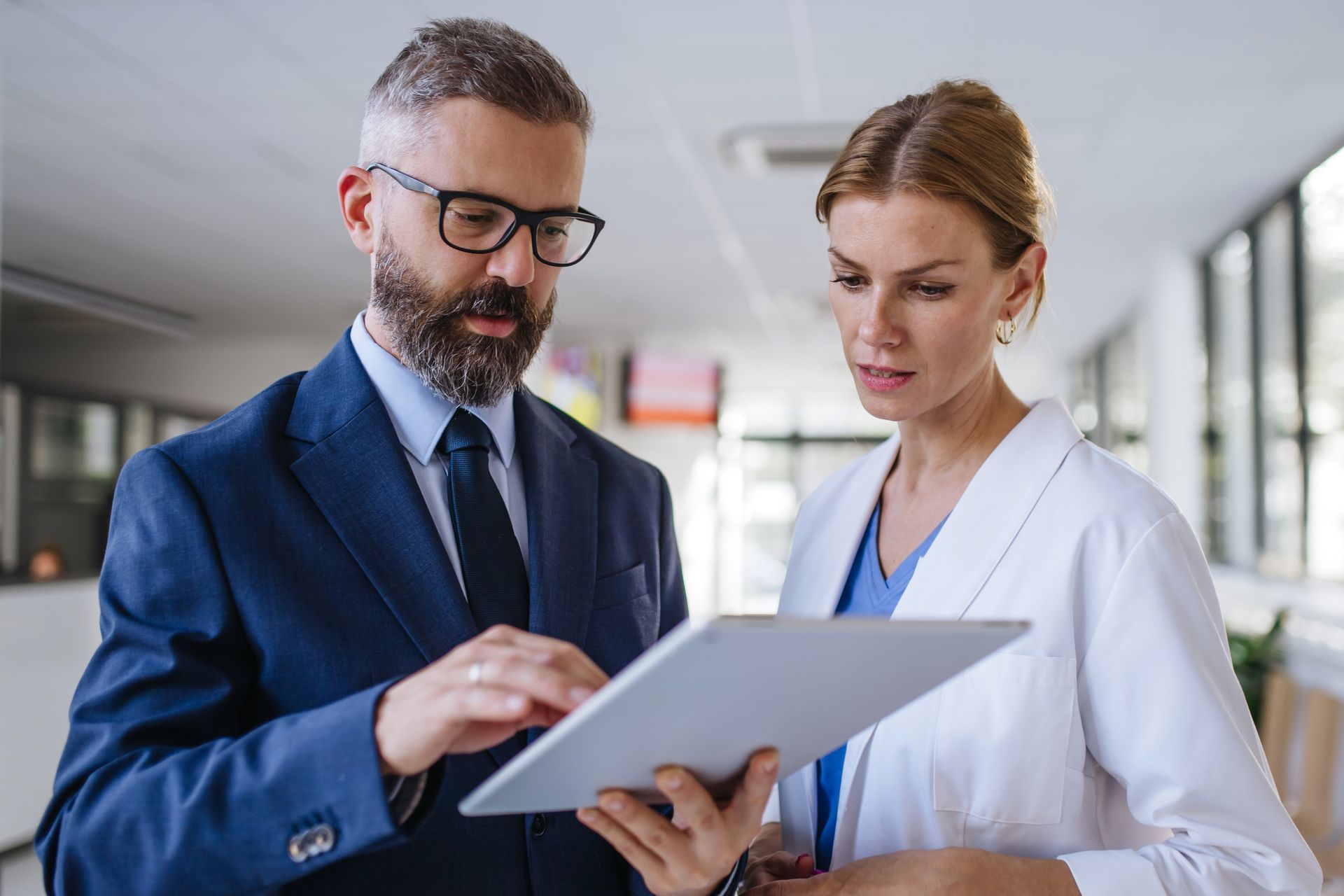Doctor smiling, reviewing chart with patient in office. White coat, stethoscope, bright setting.
