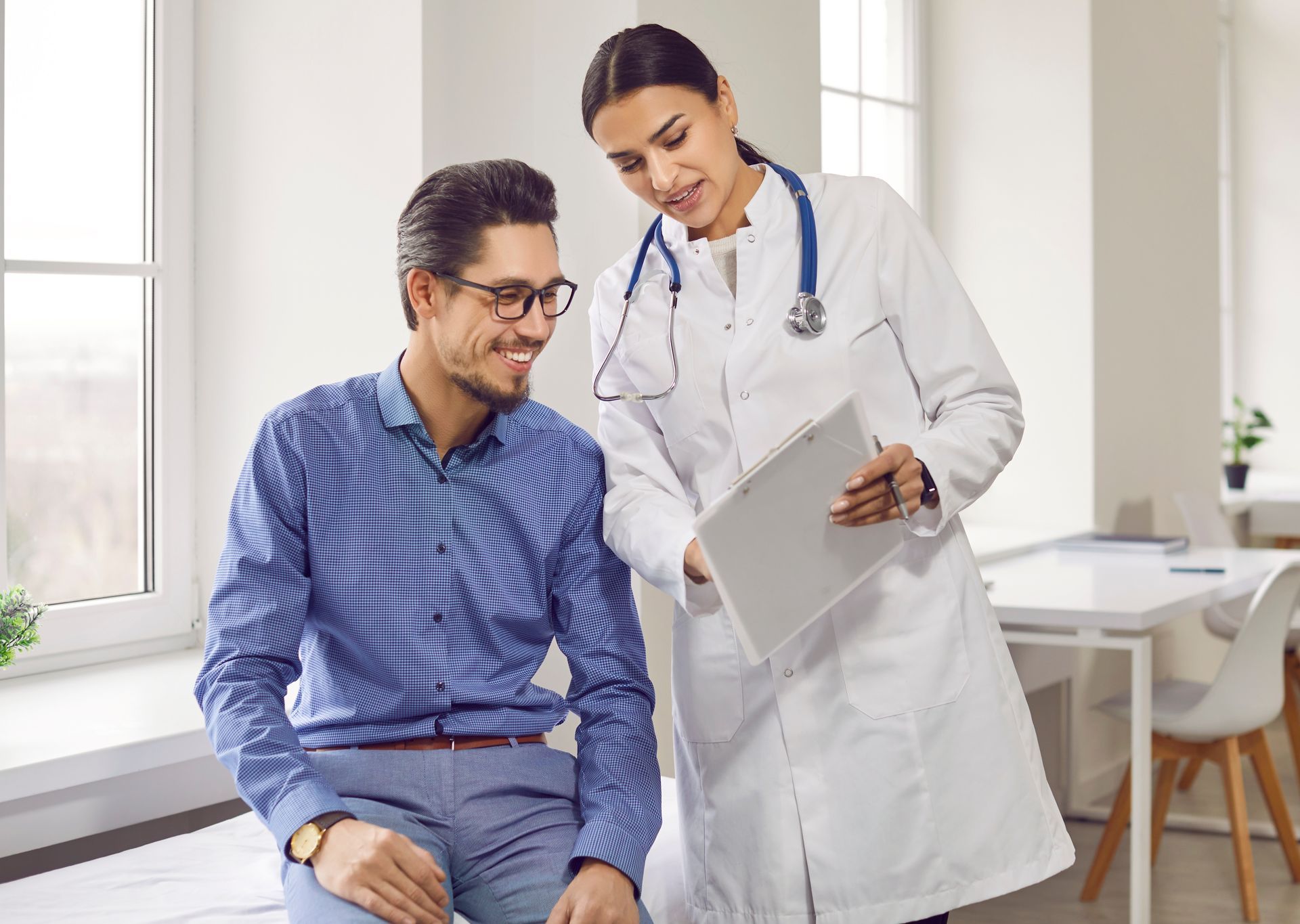 Doctor showing patient something on tablet; light-skinned, smiling, professional office.