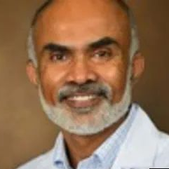 Man with beard and glasses, smiling. Wearing a white lab coat.