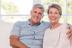 Smiling couple on couch next to window
