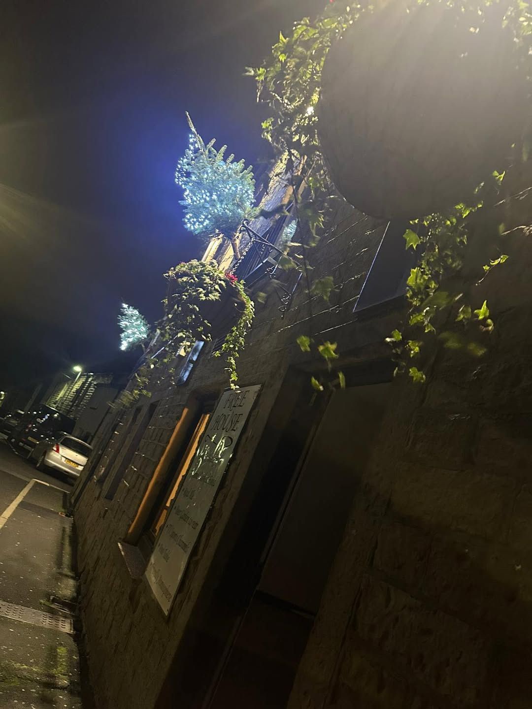 Night shot of a stone building decorated with Christmas lights and greenery.