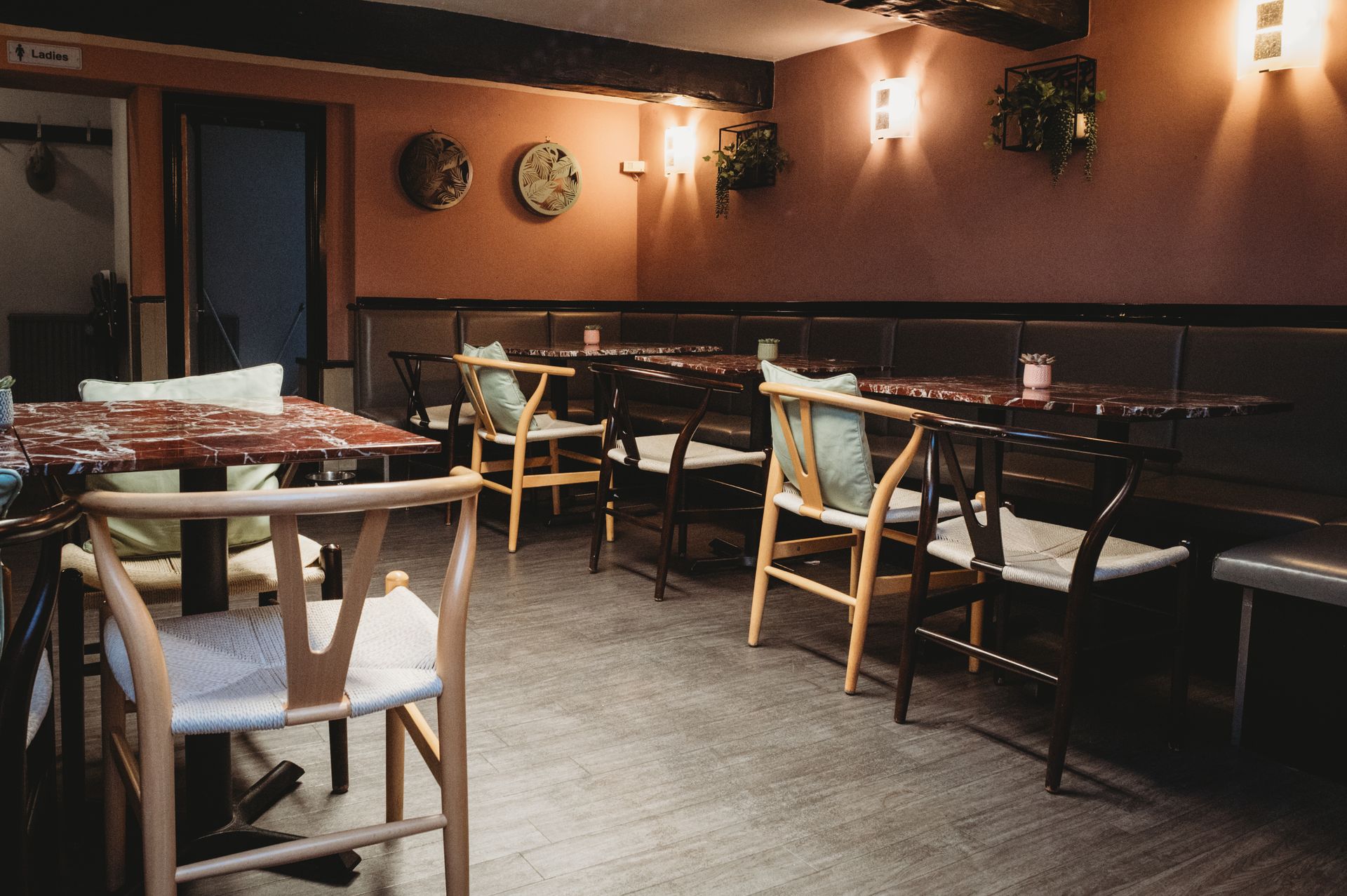 Interior of a restaurant, dark booth, and warm lighting on a pink wall. Inside the Boot & Shoe, cosy and welcoming.
