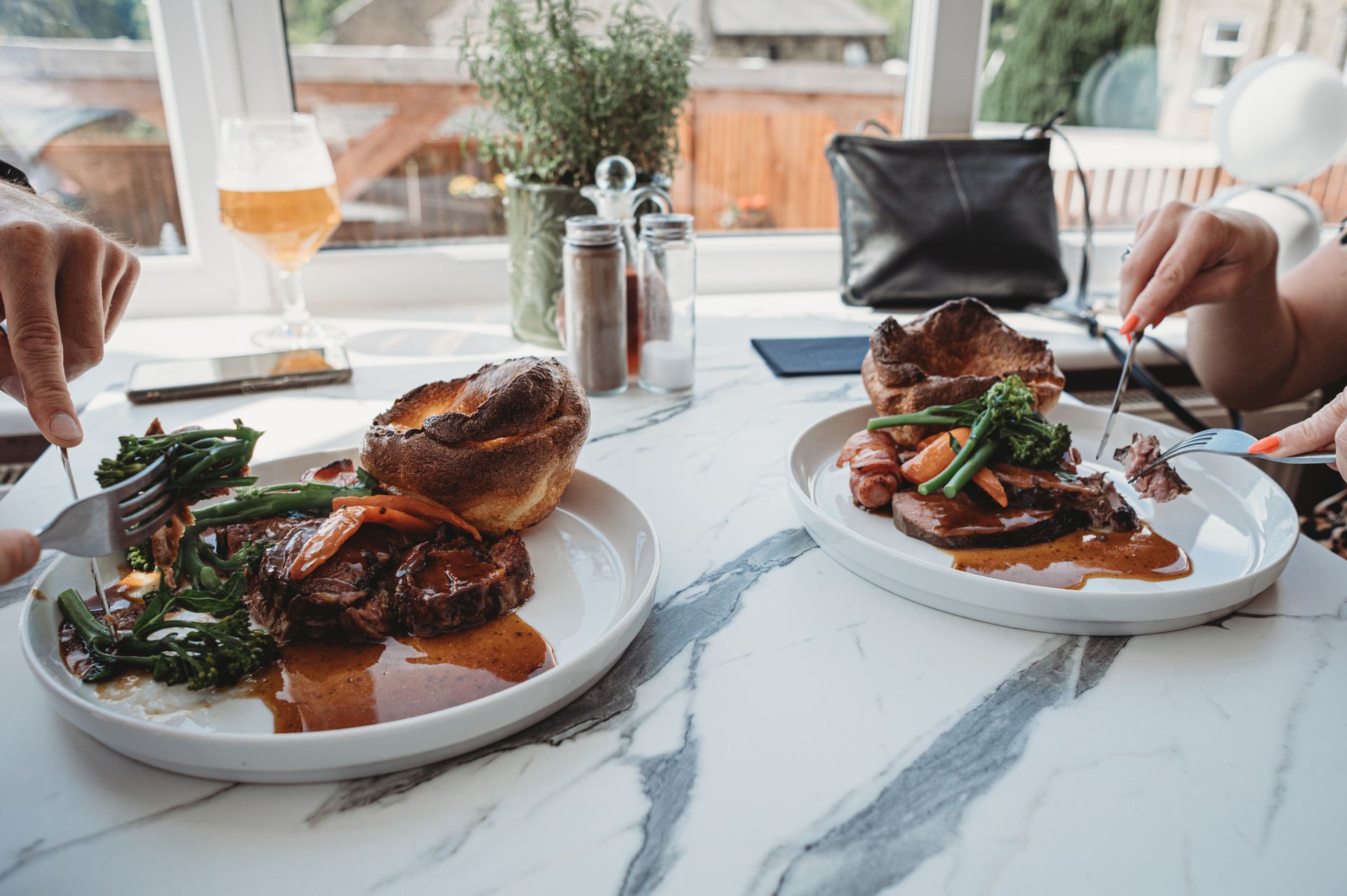 Two plates of food on a marble table; people eating dinner in a restaurant setting.