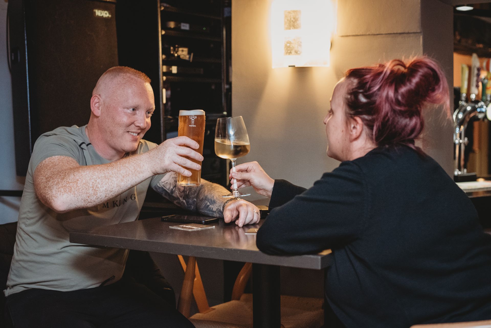 Two people toasting drinks at a table in a bar. One with beer, the other with wine. at the Boot & Shoe Waterfoot, Rossendale