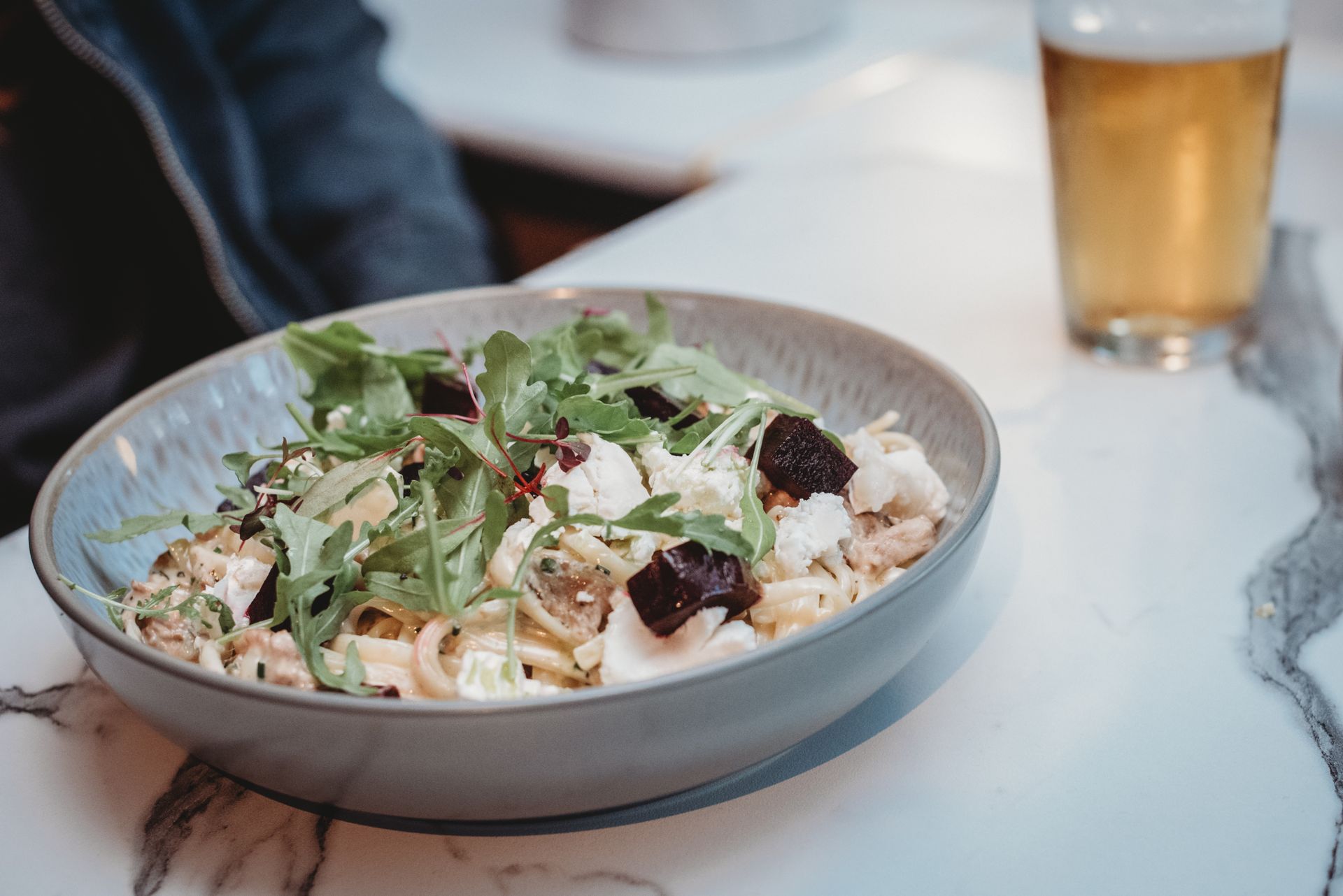 Pasta with arugula, beets, and cheese, near a beer glass. Food at the Boot & Shoe, Waterfoot, Rossendale