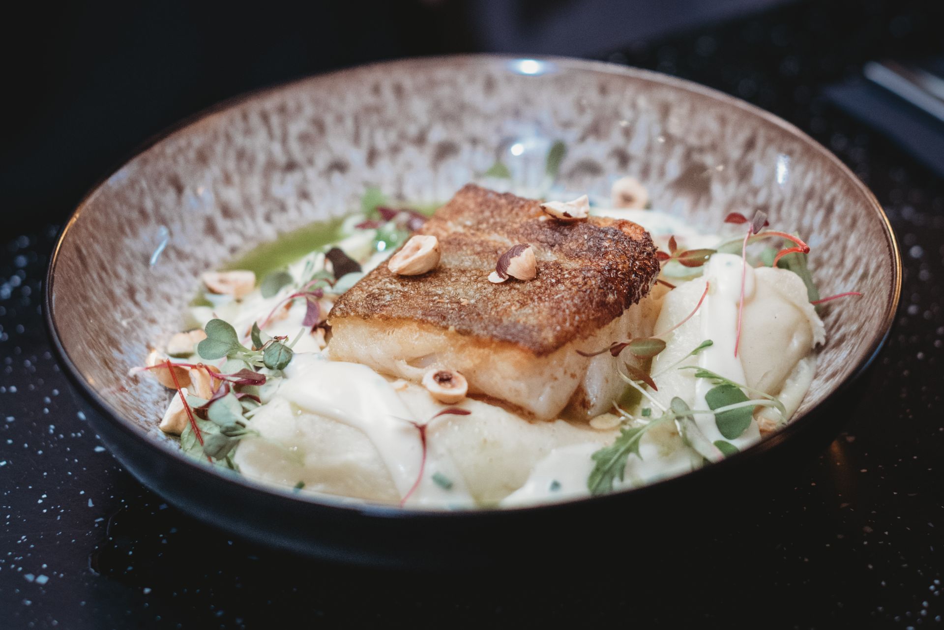 Pan-seared fish on creamy puree, garnished with nuts and herbs in a bowl. Food at the Boot & Shoe, Waterfoot, Rossendale