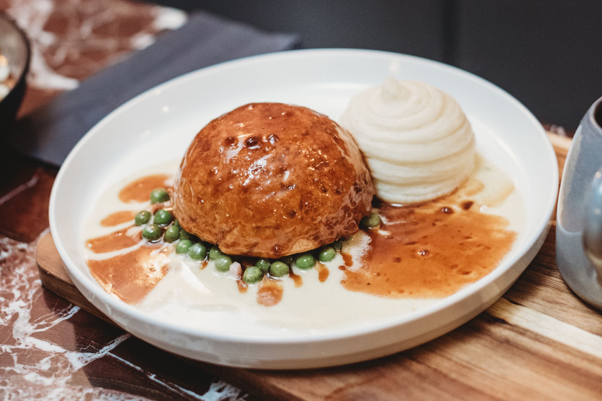 Savory meat pie on a white plate with peas, gravy, and mashed potato swirl. Food at the Boot & Shoe, Waterfoot, Rossendale