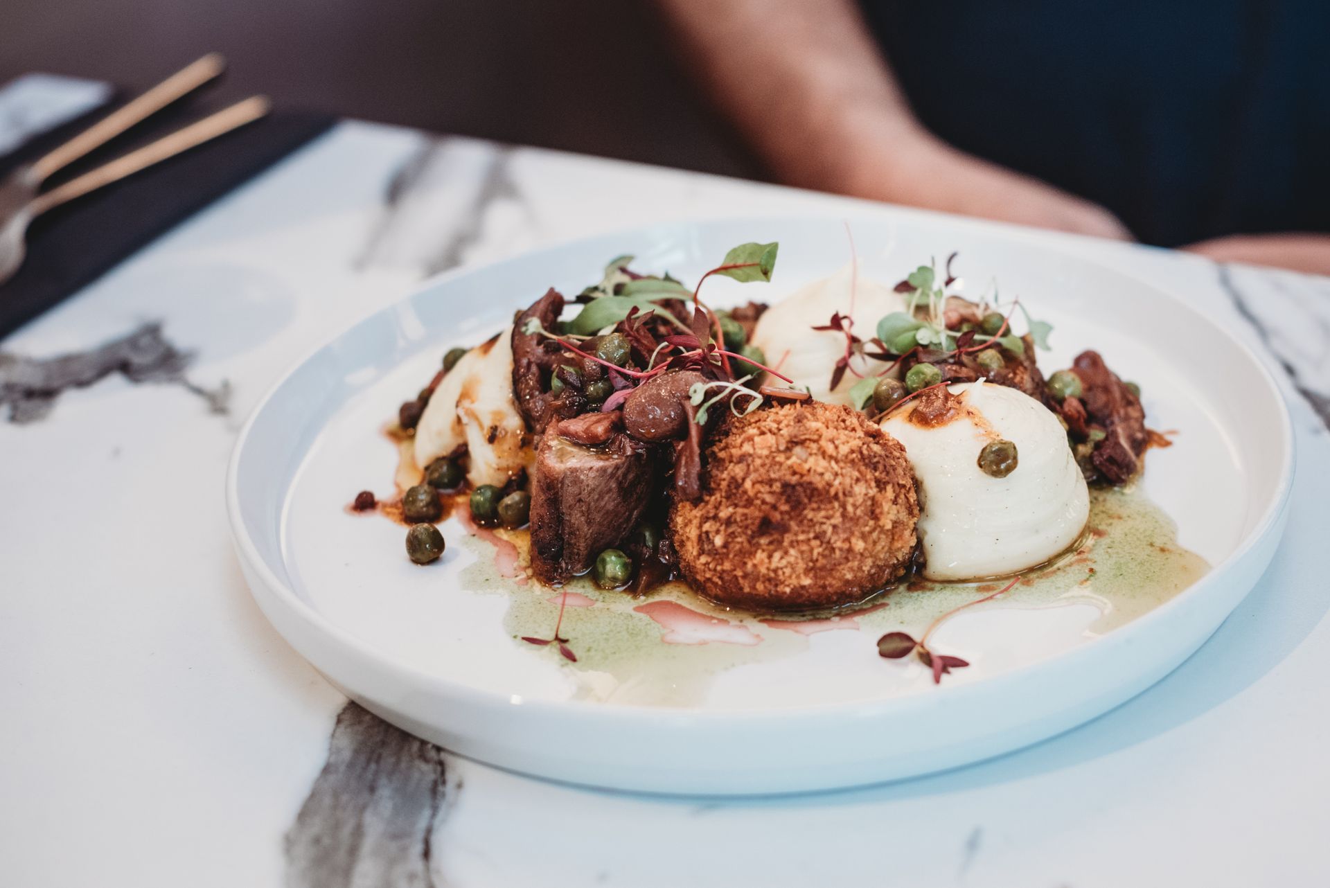 Braised meat, potato, peas, and a fried egg on a marble tabletop. Food at the Boot & Shoe, Waterfoot, Rossendale