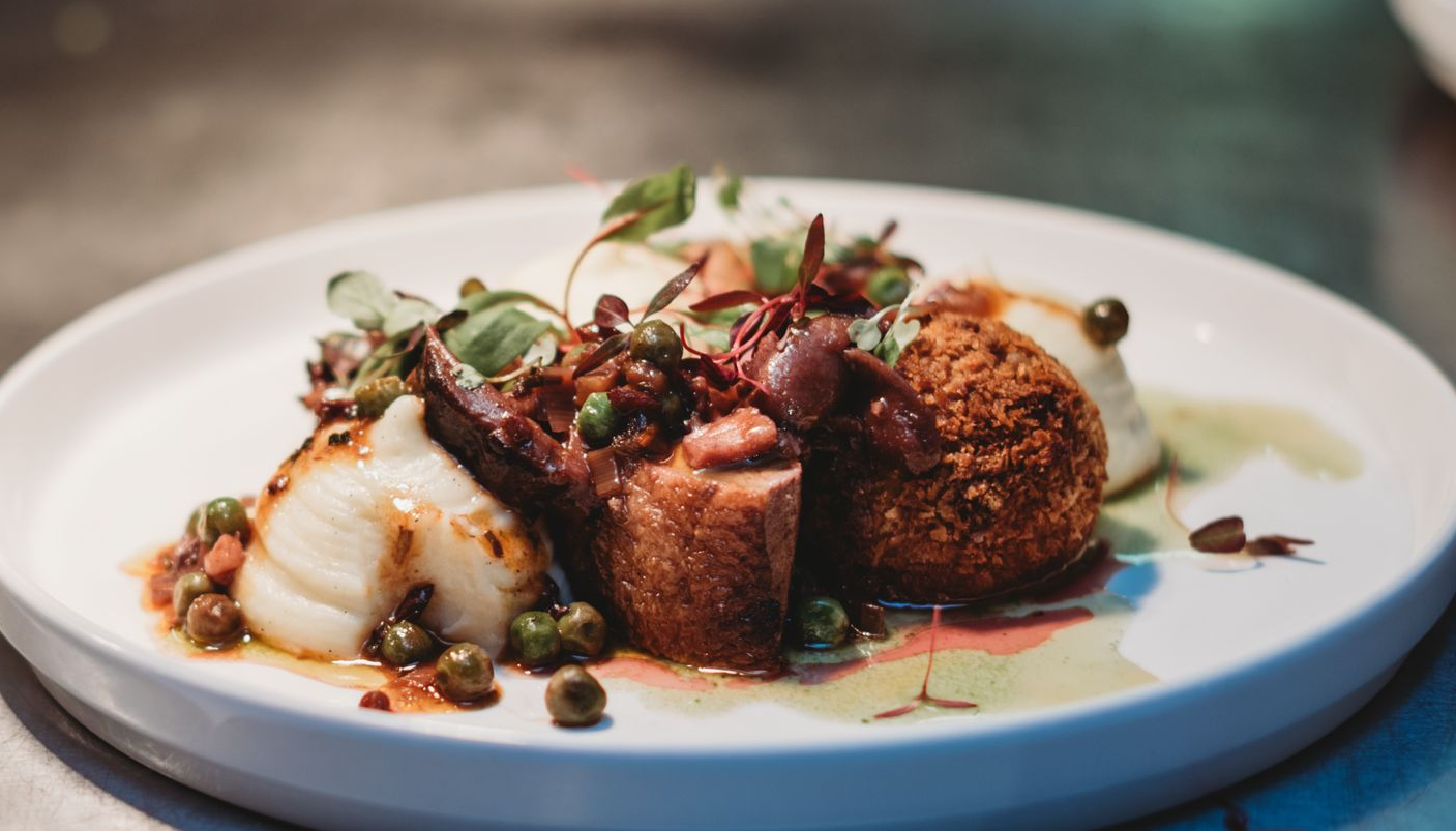 A meat pie with gravy, potatoes, and green beans on a white plate.