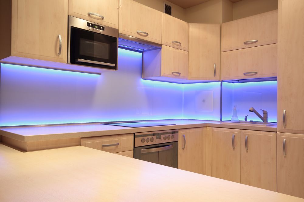 Modern kitchen with light wood cabinets, a microwave, and blue LED strip lighting along the backsplash and under the cabinets — CKS Electrical and Air Conditioning in Yulara, NT