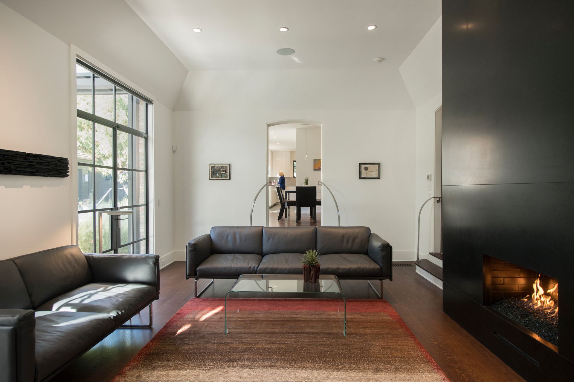 Modern living room with leather sofas, fireplace, and large windows.