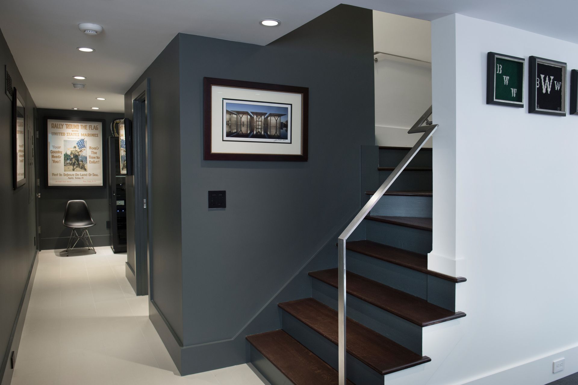 Dark gray hallway with stairs, artwork, and white trim.