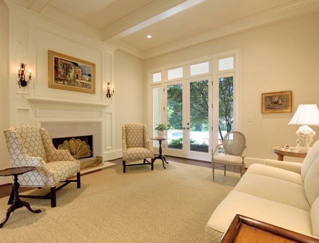 Living room with fireplace, furniture, and French doors. Light beige walls, carpet, and furniture.
