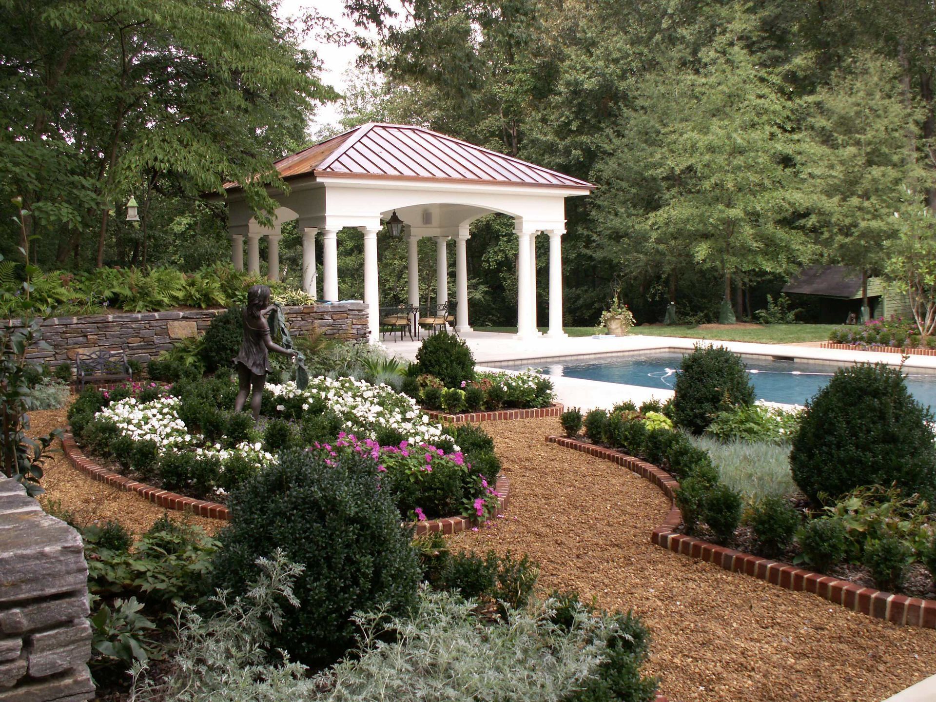 Landscaped garden with a gazebo, flowerbeds, and a pool.