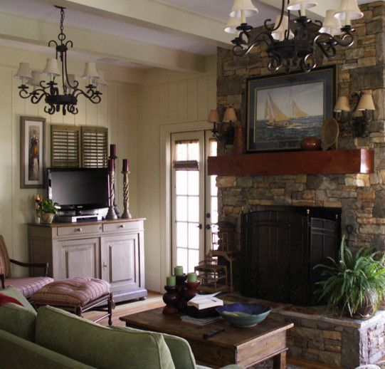 Living room with stone fireplace, TV, and green sofa. Warm, inviting with soft lighting.