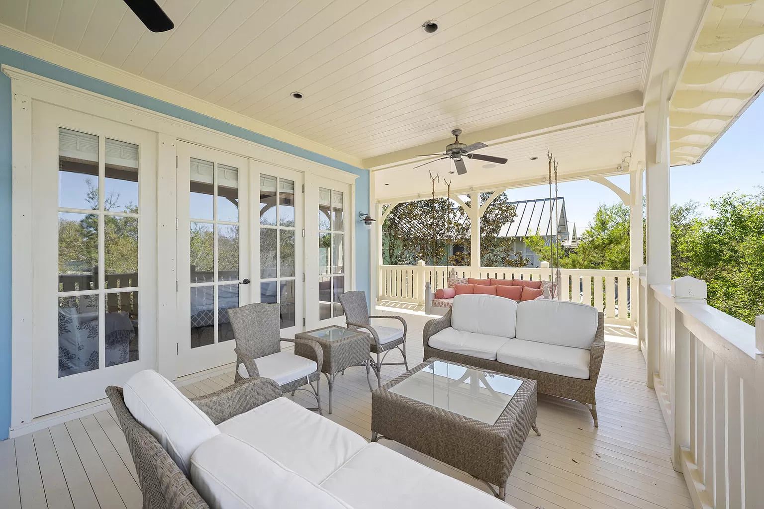 Outdoor porch with seating, white furniture, and blue accents.