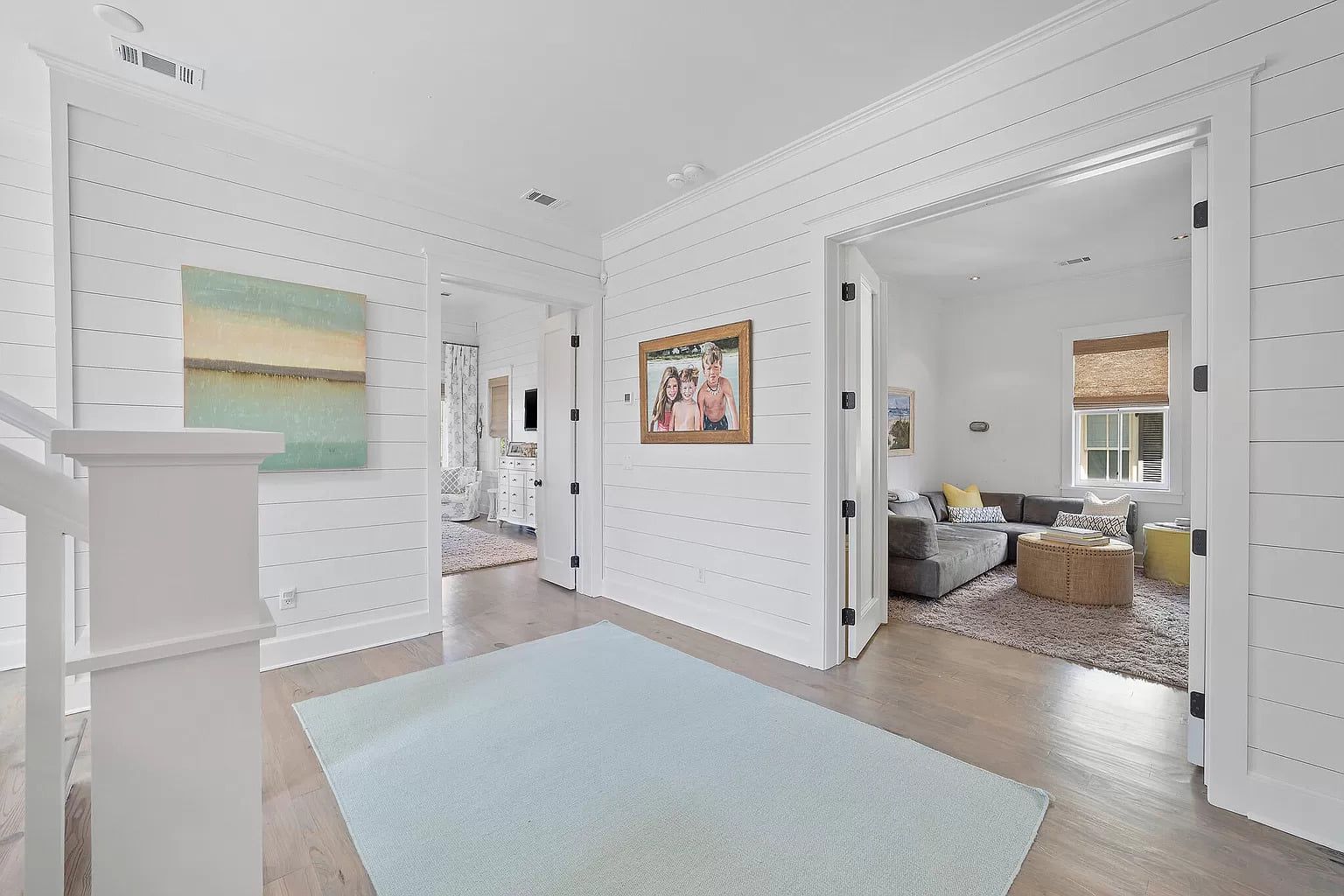 Hallway with light blue rug, white walls, and doorways leading to rooms.