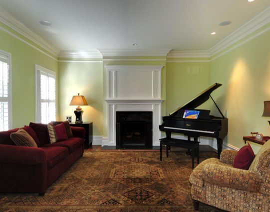 Living room with a red couch, black piano, and fireplace. Green walls, brown rug.