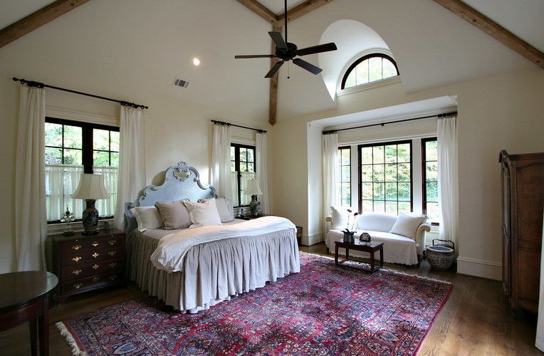 Bedroom with high ceilings, large windows, and a floral rug.