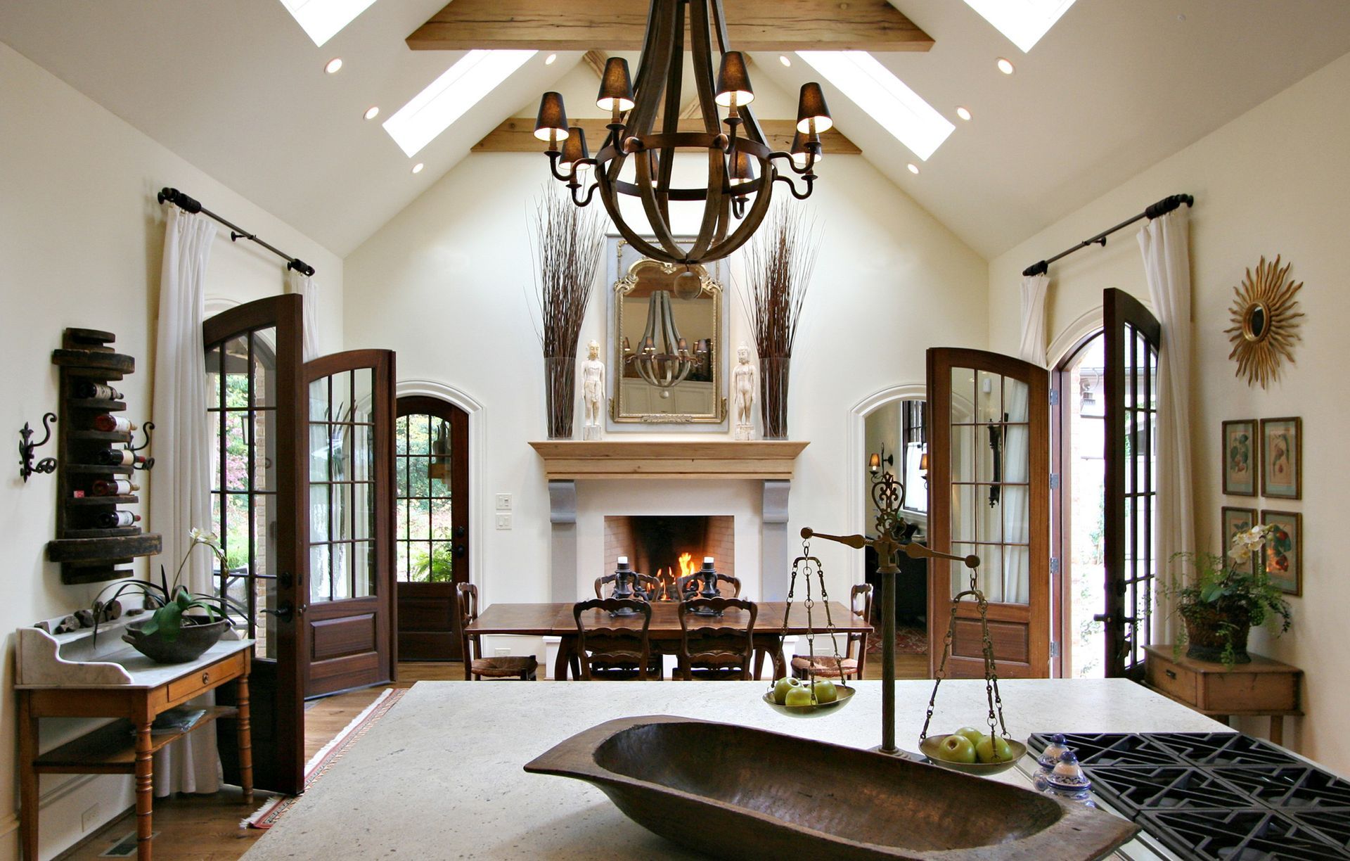 Elegant dining room with fireplace, chandelier, arched doorways, and a kitchen island.
