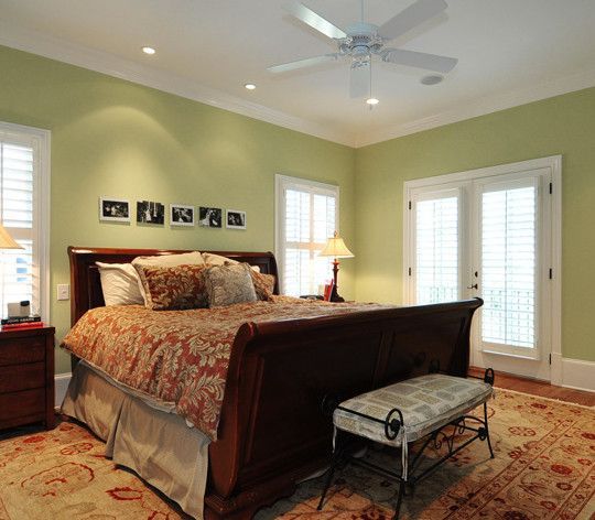 Bedroom with a large bed, green walls, and a patterned rug.