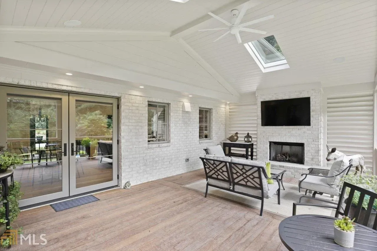Covered outdoor living space with fireplace, TV, and seating.