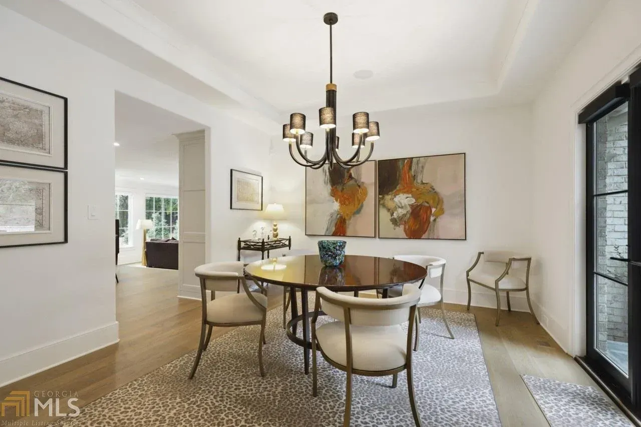 Dining room with chandelier, table, chairs, artwork, and door.