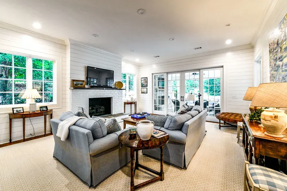 Living room with blue sofas, brick fireplace, and doors leading to a patio.