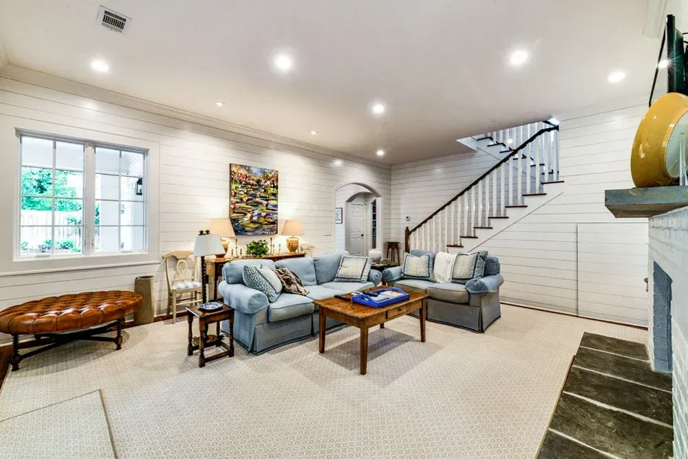 Cozy living room with blue sofa, stairs, and white brick fireplace.