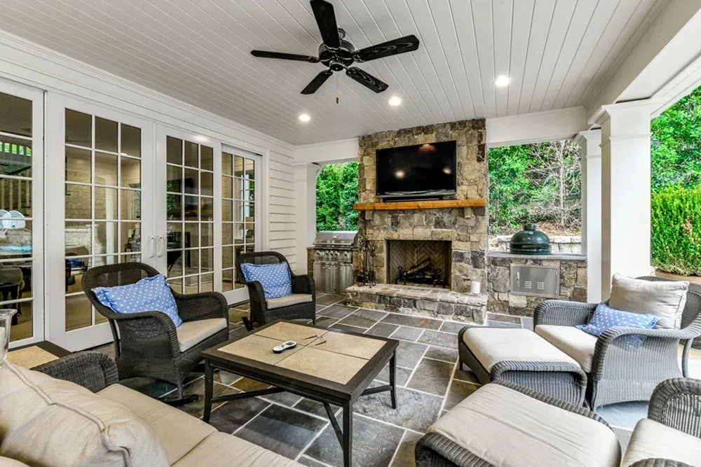 Outdoor patio with seating, fireplace, TV, and a ceiling fan.