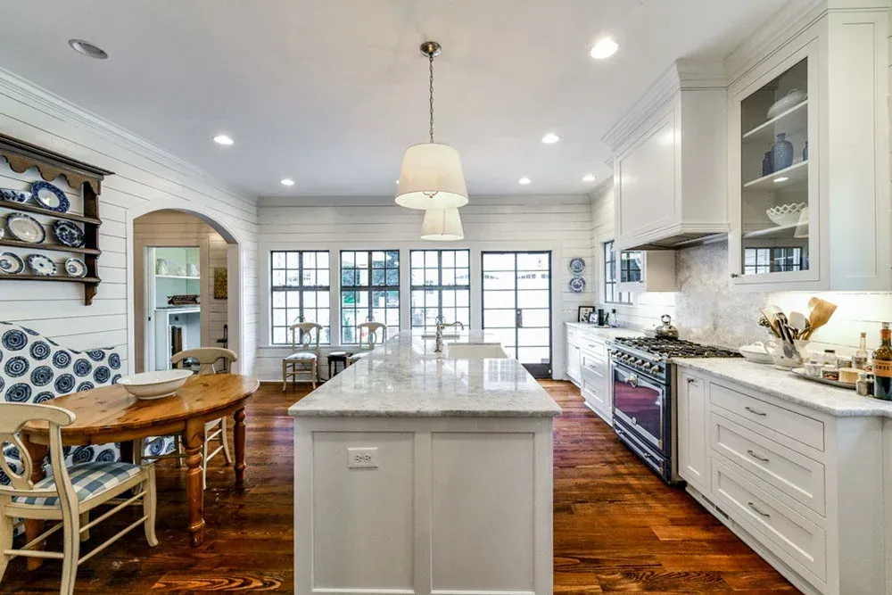 Bright white kitchen with island, wood floors, and large windows.