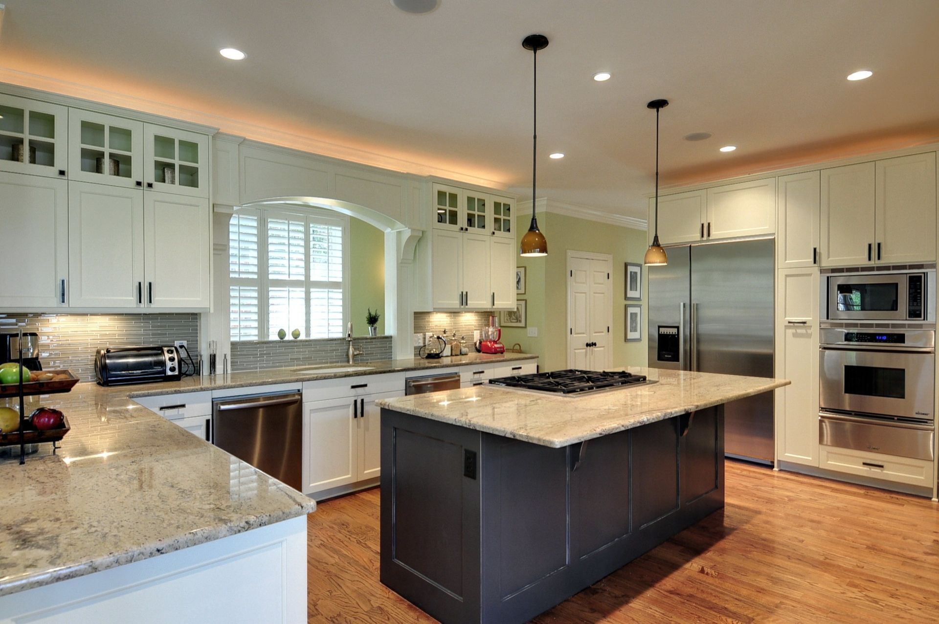 Modern kitchen with white cabinets, granite countertops, and a dark gray island.