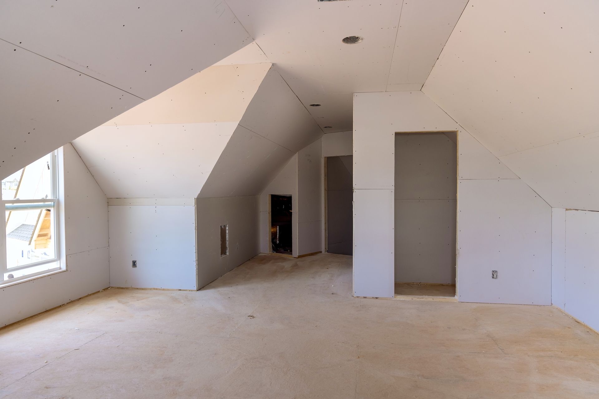 An empty attic in a house under construction with a vaulted ceiling.