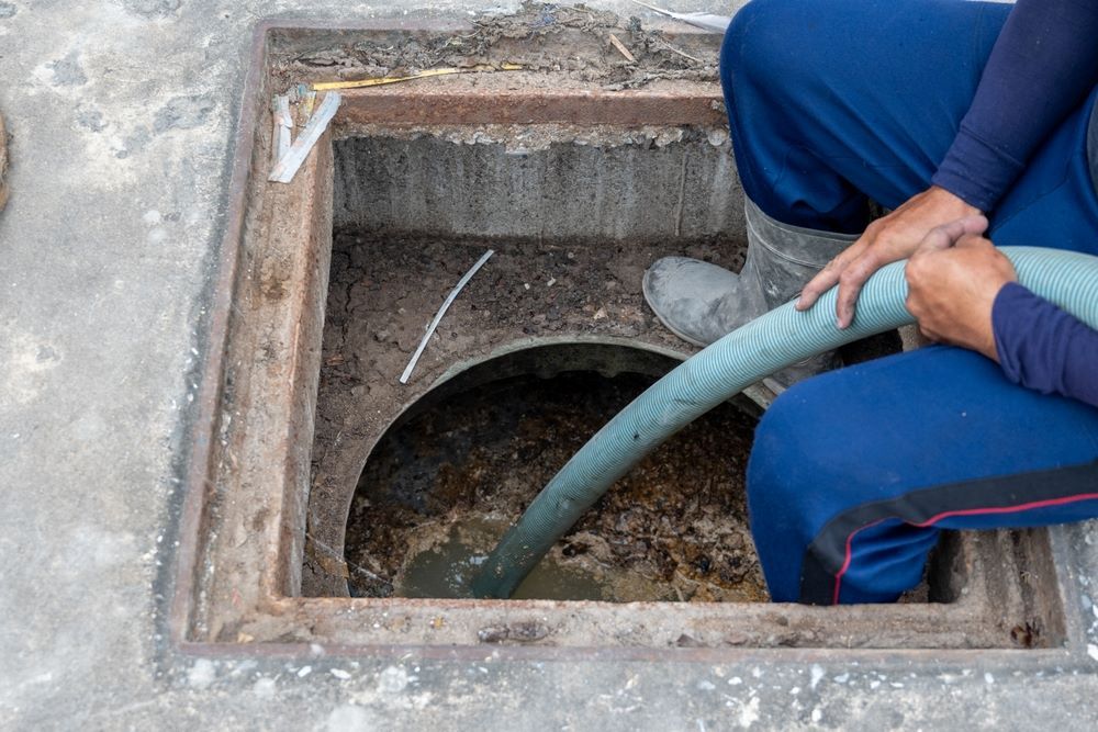 A Man is Pumping Water Into a Manhole Cover With a Hose — Pootanky Byron Bay, NSW
