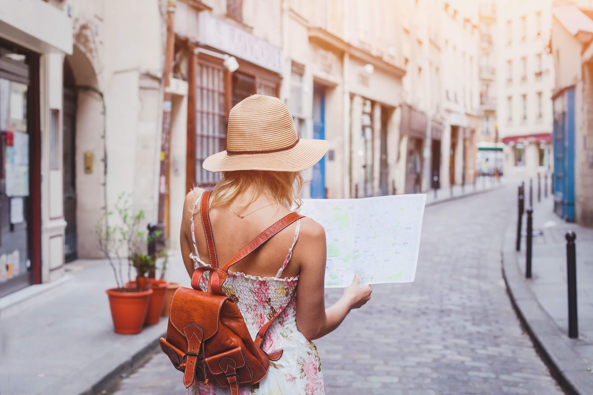 A woman is walking down a cobblestone street holding a map.