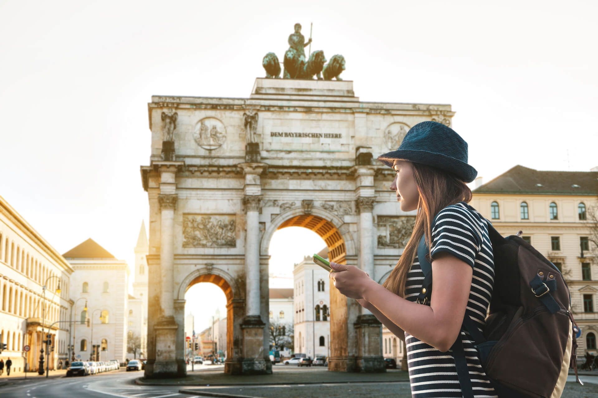A woman with a backpack is looking at a map in front of the Arc de Triomphe du Carrousel 