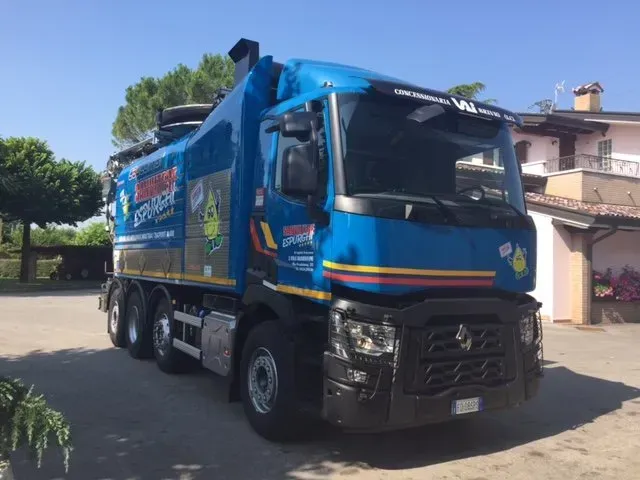 Un camion della spazzatura blu è parcheggiato davanti a una casa.