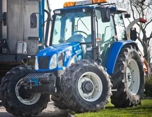 Un trattore blu e bianco è parcheggiato nell'erba
