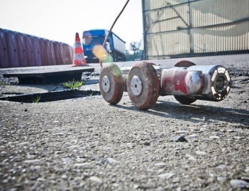 Un robot è seduto a terra accanto a un tombino