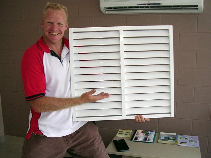 Man Holding a White Louvered Window, Smiling, Indoors — Lifestyle Aluminium Lattice in West End, QLD