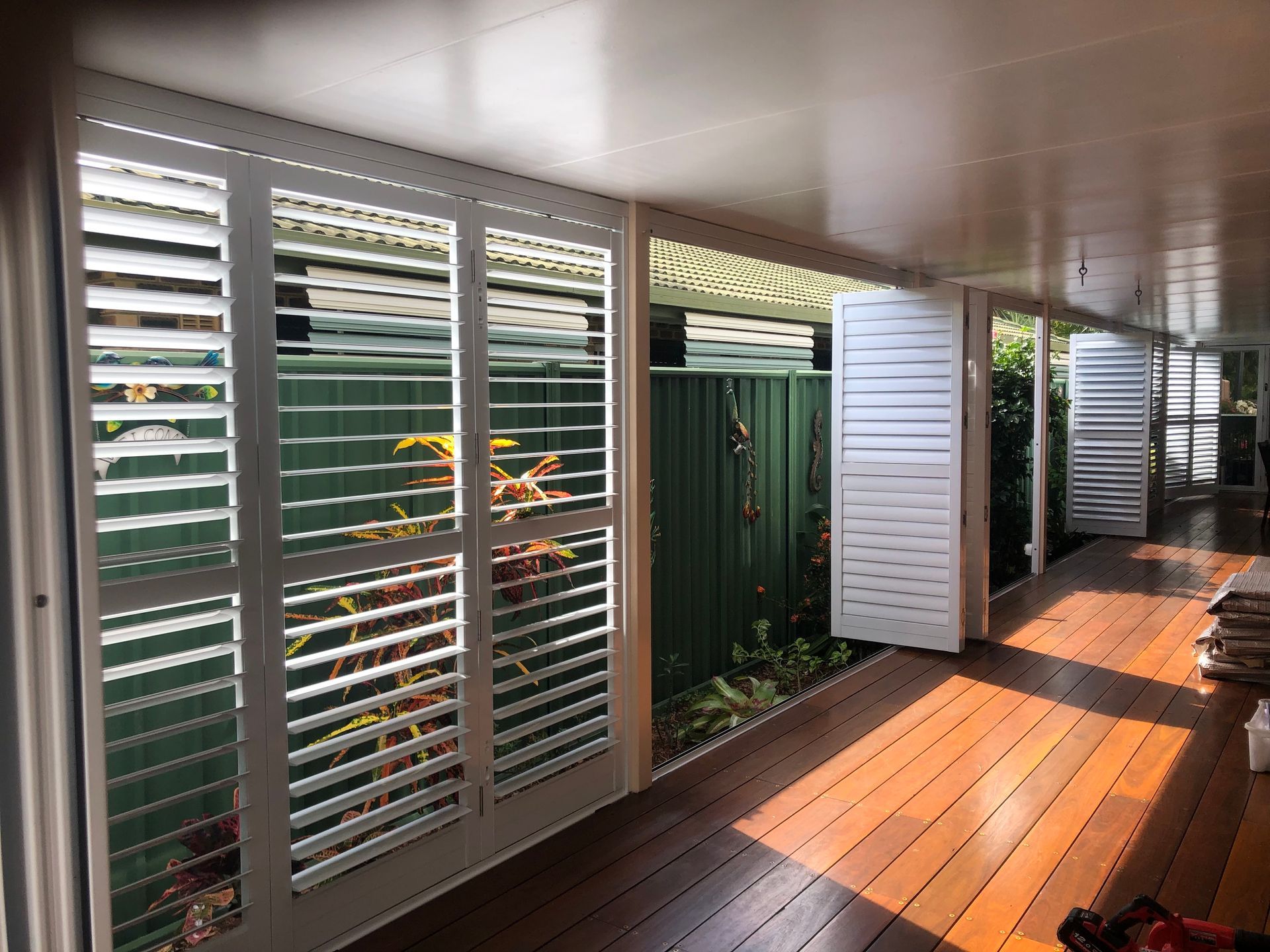 White Louvered Shutters on a Porch With Wooden Floors — Lifestyle Aluminium Lattice in Kirwan, QLD