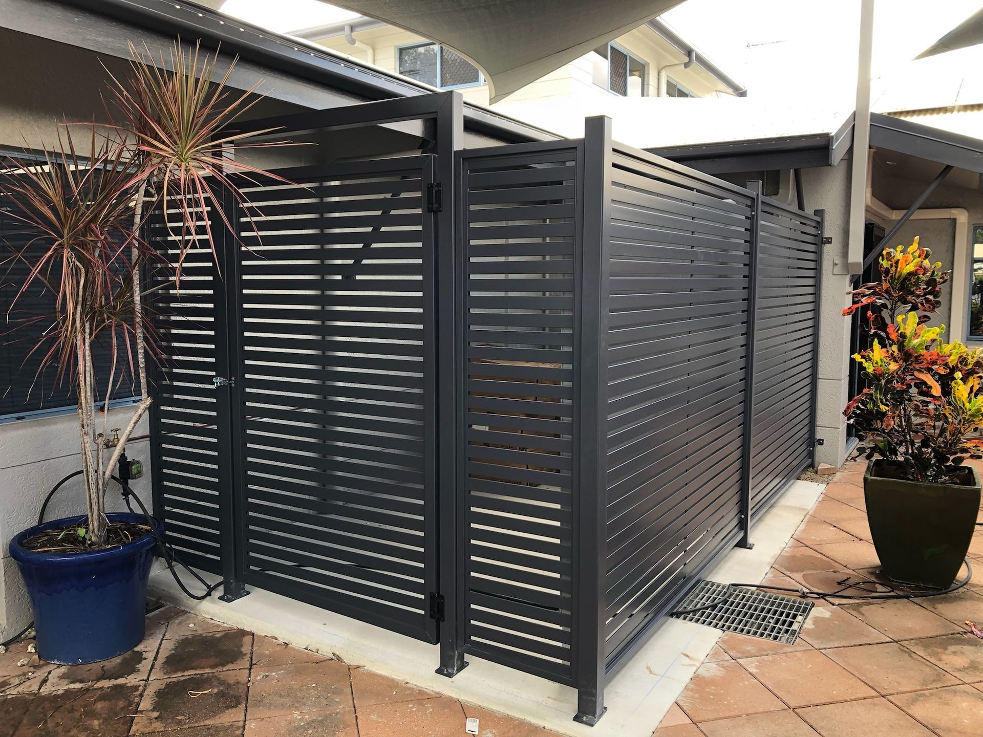 Dark Gray Slatted Privacy Fence in a Courtyard With Potted Plants — Lifestyle Aluminium Lattice in West End, QLD