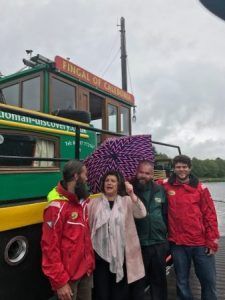 Four people stand by a green and yellow boat, 
