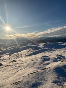 Snowy mountain landscape under a bright sun, blue sky with thin clouds.