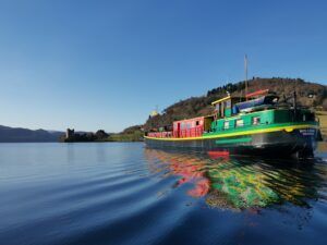 Colorful boat on Loch Ness with Urquhart Castle in the distance.