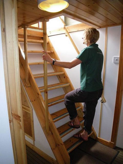 Woman in green shirt climbing wooden stairs toward a light.