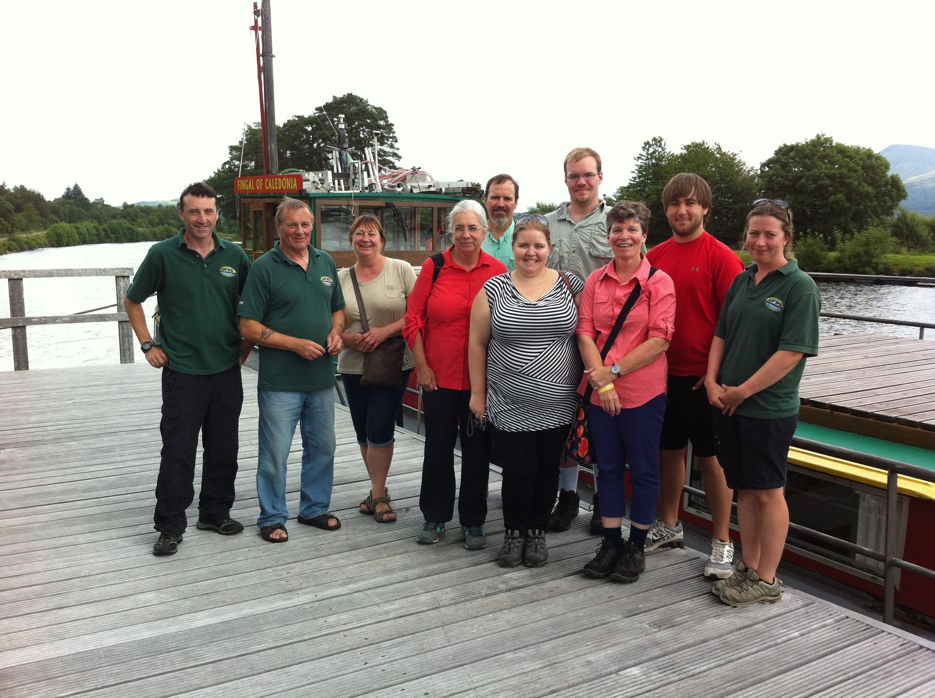 A group of people standing on a dock next to a boat with the word 
